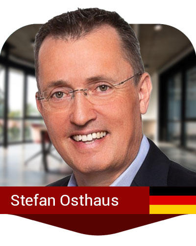 A man with short brown hair and glasses smiles at the camera in a modern office setting. Text on the image reads "Stefan Osthaus" with a German flag icon.