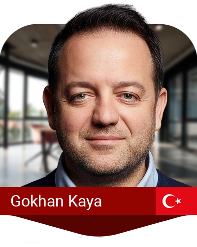 A man smiles at the camera in a modern office setting. A red banner at the bottom displays the name "Gokhan Kaya" and a Turkish flag.